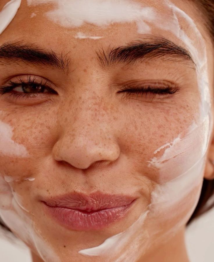 Femme appliquant des soins sur son visage avec de la mousse nettoyante
